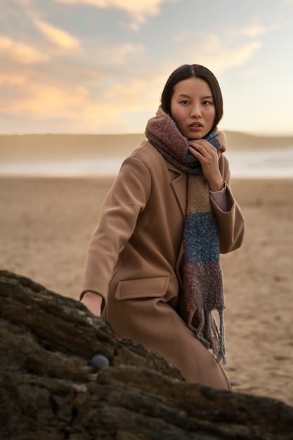 A close-up of a Korean drama actress wearing a long, sophisticated trench coat in a neutral color, showcasing its elegant details and silhouette.