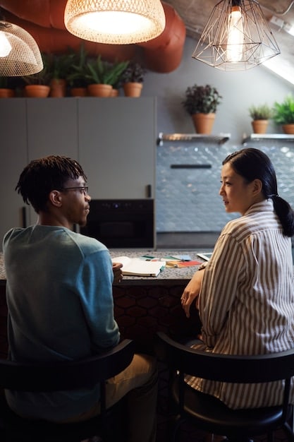 Two colleagues in a Korean drama are having a subtle conversation in a busy office. Their facial expressions and gestures convey deeper meanings than their words, highlighting the importance of non-verbal communication.