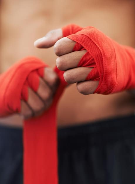 Close-up of Jang Hyuk's hands wrapped in boxing tape. His knuckles are slightly bruised, indicating intense training. The background is blurred, focusing solely on his hands.