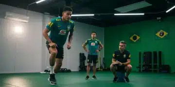 Atleta brasileiro em treinamento intenso, com psicólogo esportivo ao fundo, focado na alta performance e preparação mental para 2025.