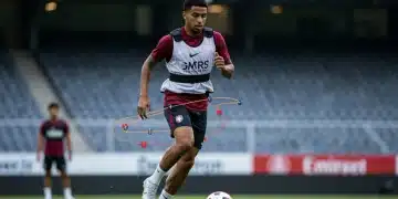 Jogador de futebol em treinamento intensivo com colete de GPS, simbolizando a modernização do preparo físico no Brasil. Foco na ciência do esporte e tecnologia.